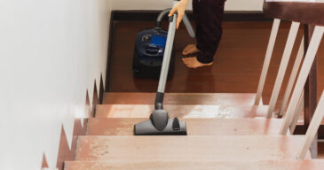 Asian young housekeeper hoovering stairwell in a house